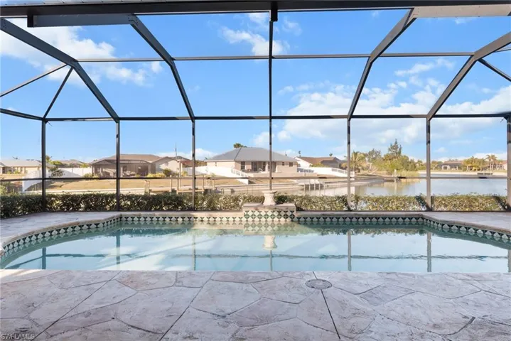 View of swimming pool featuring glass enclosure and a water view