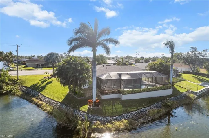 Back of property with a yard, a water view, and glass enclosure