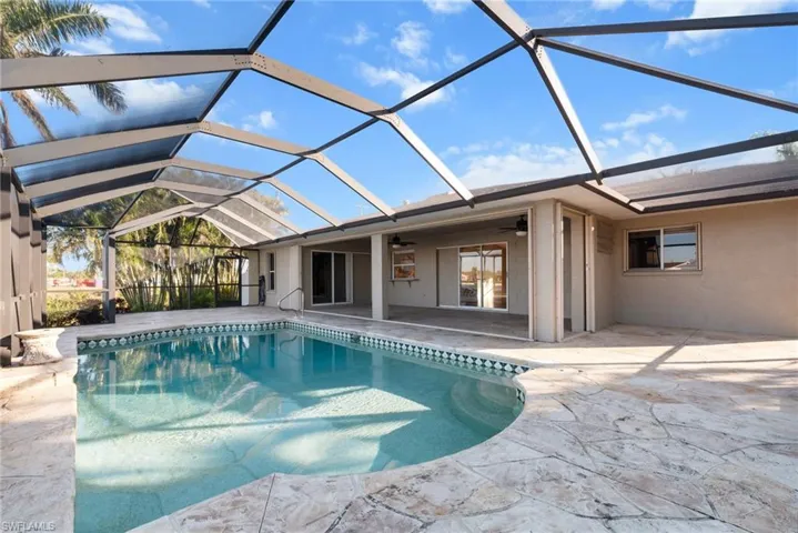 View of swimming pool featuring a patio, glass enclosure, and ceiling fan