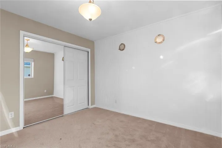 Unfurnished bedroom with light carpet and a closet