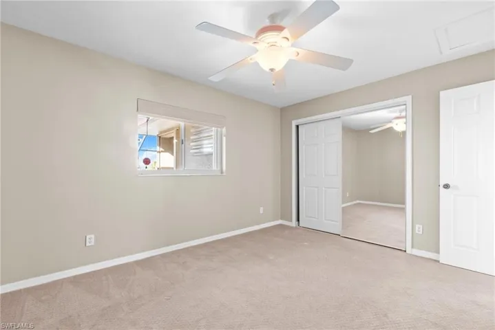 Unfurnished bedroom featuring ceiling fan, a closet, and light carpet