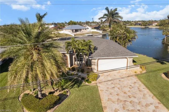 View of front of property featuring a garage, a water view, and a front lawn