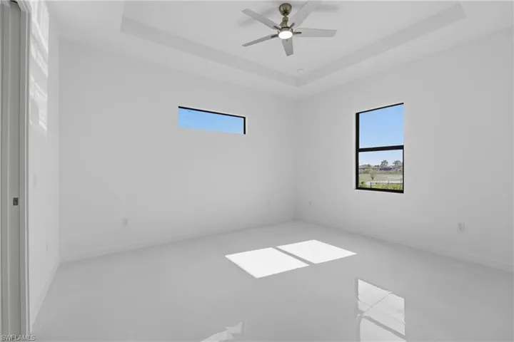 Spare room with plenty of natural light, a tray ceiling, and ceiling fan