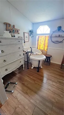 Bathroom featuring a freestanding bath, a textured ceiling, and wood finished floors