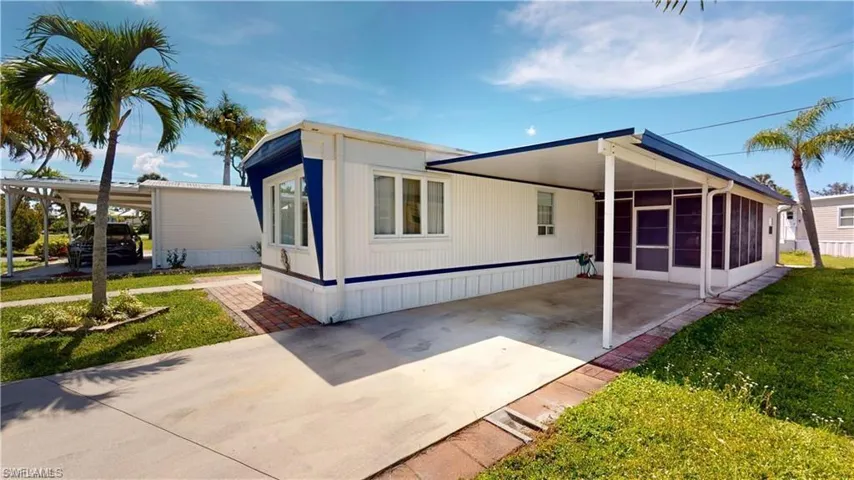 Front view of home with a yard, a carport, and a sunroom