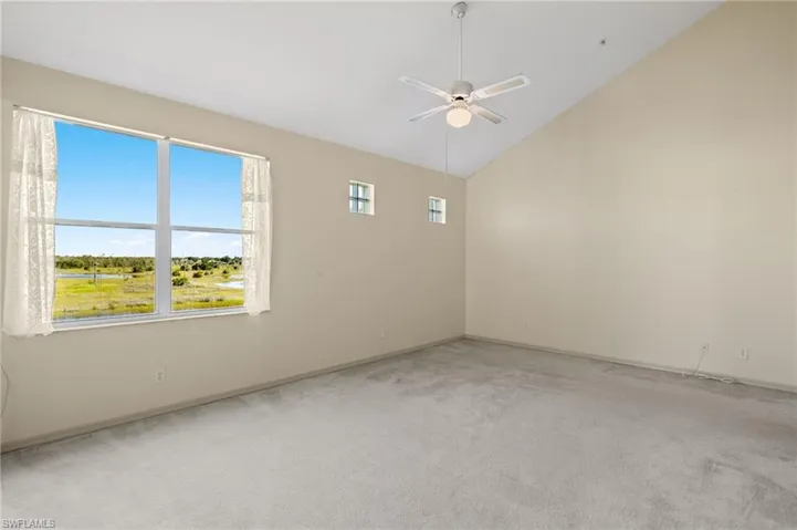 Unfurnished room featuring ceiling fan, light colored carpet, and high vaulted ceiling