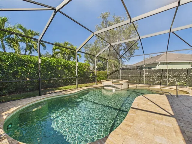 View of swimming pool featuring a pool with connected hot tub, glass enclosure, and a sunroom