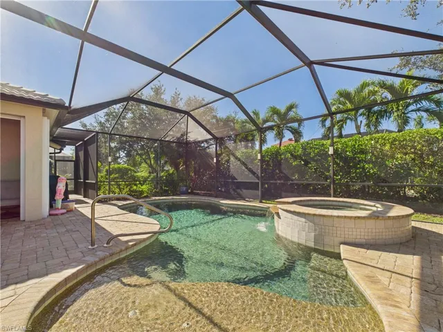 View of swimming pool with a patio, glass enclosure, a sunroom, and a pool with connected hot tub