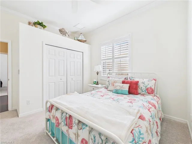 Bedroom featuring light carpet, a closet, ornamental molding, and a ceiling fan
