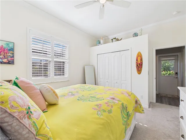 Bedroom featuring light colored carpet, a closet, a ceiling fan, and ornamental molding
