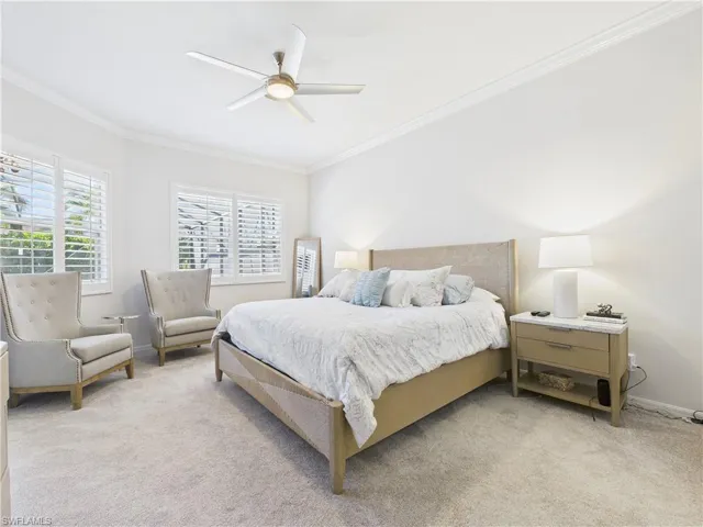 Carpeted bedroom featuring ornamental molding and ceiling fan