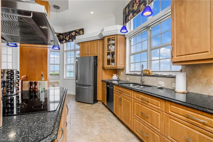 Kitchen featuring sink, stainless steel refrigerator, range hood, and tasteful backsplash