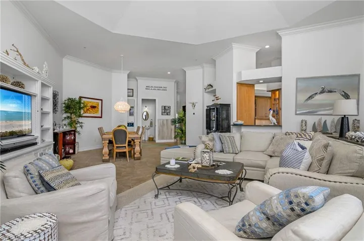 Living room featuring crown molding, built in shelves, and tile patterned floors