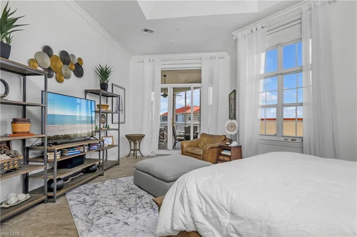 Bedroom featuring light tile patterned flooring, crown molding, and multiple windows