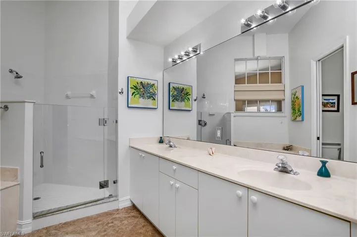 Bathroom with toilet, tile patterned floors, an enclosed shower, and double vanity