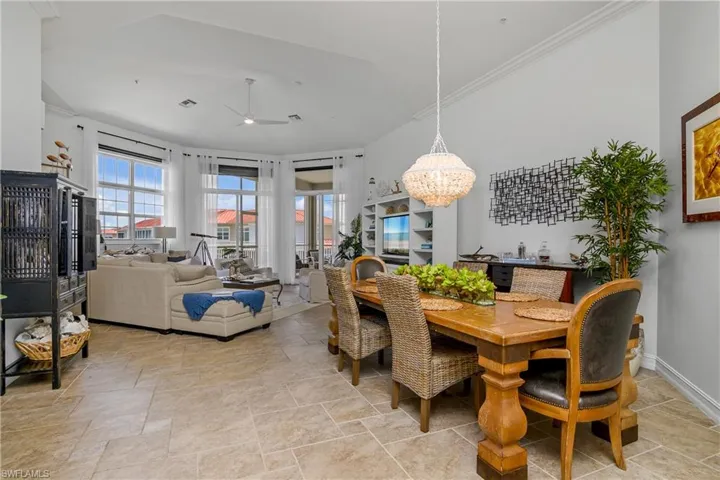 Tiled dining space with ceiling fan with notable chandelier and crown molding