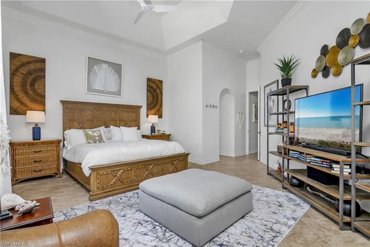 Bedroom with light tile patterned floors, ceiling fan, and crown molding