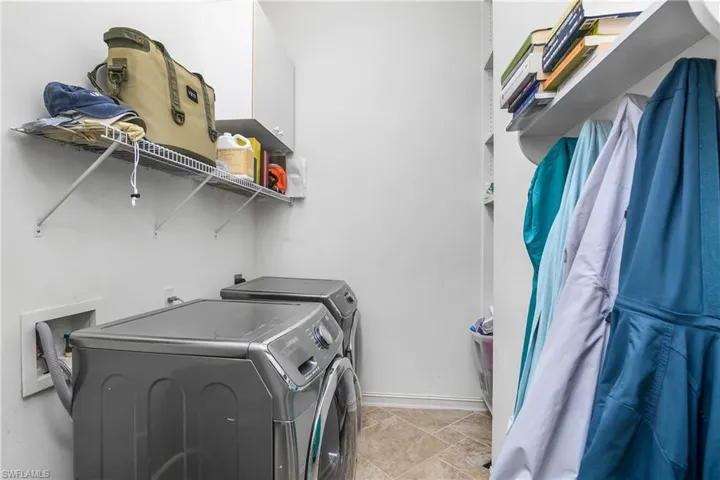 Clothes washing area featuring washing machine and dryer and light tile patterned floors