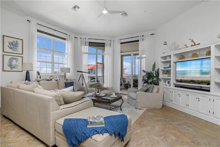 Tiled living room featuring built in shelves and ceiling fan