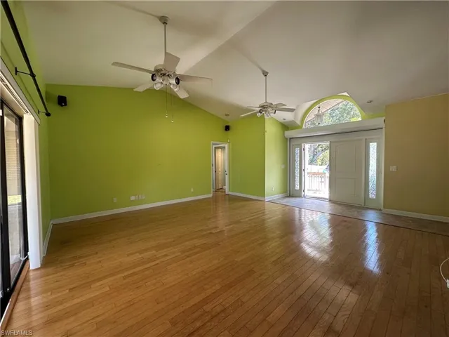 Solid Double Doors (Roll Down Hurricane Shutters) & Entry Area with Open Living Room Featuring Light Real WOOD Finished Floors and Vaulted Ceiling