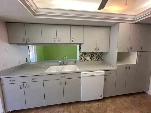 Kitchen featuring White Appliances, Light Gray Countertops, Backsplash, and a Tray Ceiling