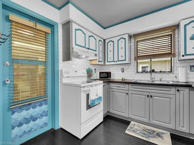 Kitchen featuring white electric range oven, sink, gray cabinets, and tasteful backsplash