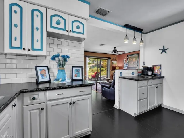 Kitchen featuring ceiling fan, decorative backsplash, pendant lighting, and white cabinets