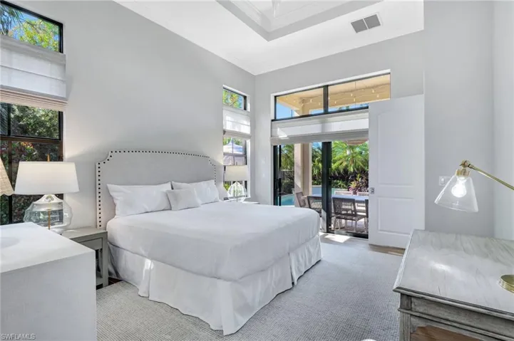 Master Bedroom featuring access to outside lanai, multiple windows, ceiling fan, and a towering ceiling