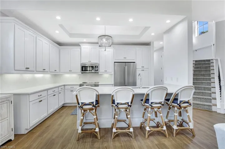 Kitchen featuring white cabinets, decorative light fixture, stainless steel Italian appliances, and a tray ceiling