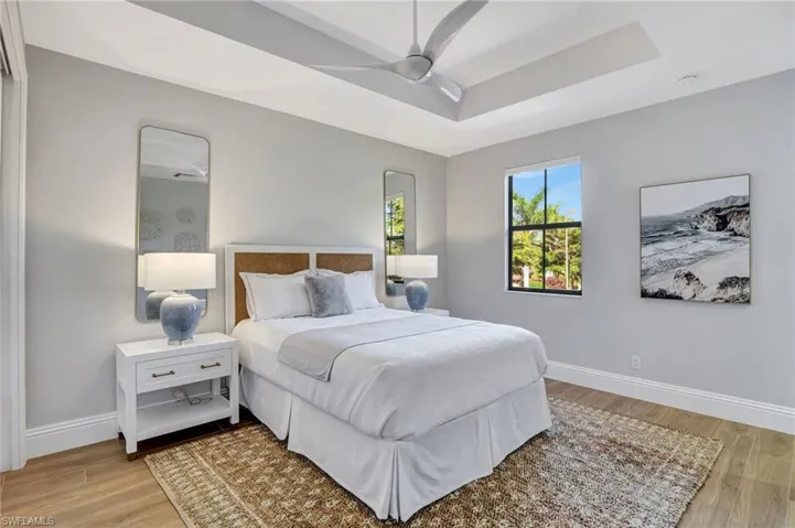 Second floor Guest Bedroom featuring ceiling fan, porcelain wood look tile flooring, and a tray ceiling