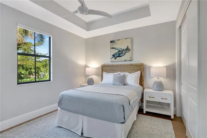 Second guest Bedroom on second floor with ceiling fan, porcelain wood look flooring and tray ceiling