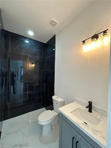 Bathroom with vanity, toilet, a shower with door, and tile patterned floors