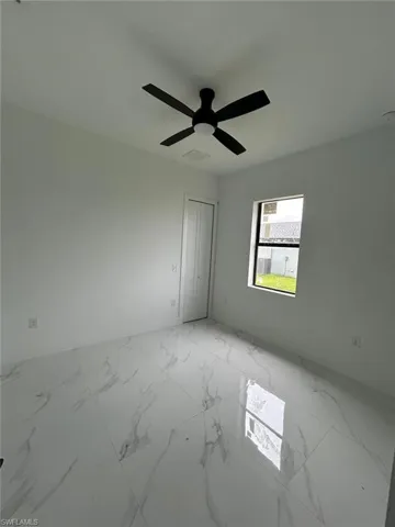 Empty room featuring light tile patterned flooring and ceiling fan