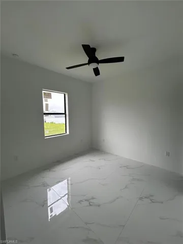 Tiled spare room featuring ceiling fan