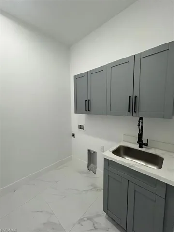 Washroom with electric dryer hookup, sink, cabinets, and hookup for a washing machine