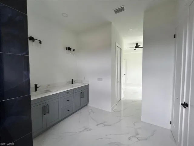 Bathroom with tile patterned flooring, ceiling fan, and dual bowl vanity