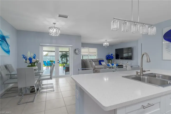 Kitchen with open floor plan, white cabinetry, a chandelier, decorative light fixtures, and light tile patterned flooring