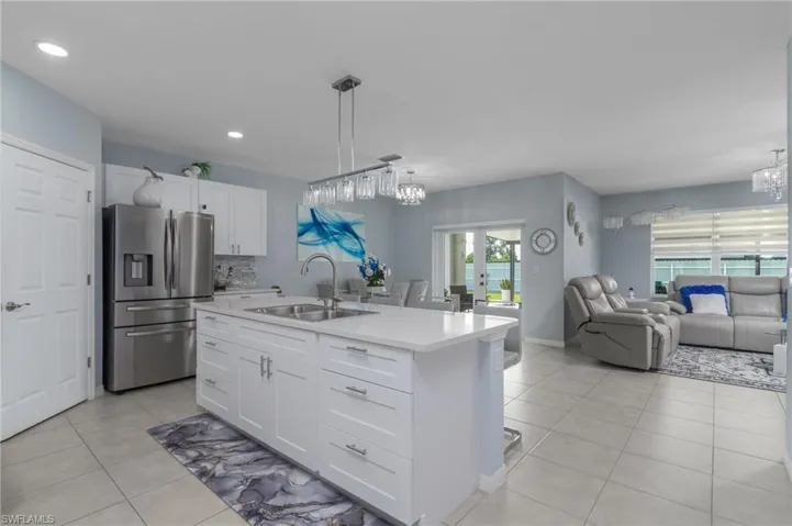 Kitchen with a chandelier, stainless steel fridge, open floor plan, light tile patterned floors, and recessed lighting
