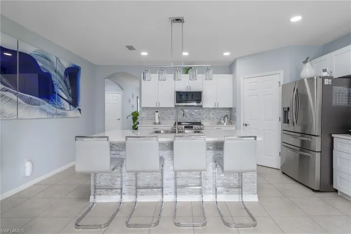 Kitchen featuring stainless steel appliances, light countertops, tasteful backsplash, light tile patterned flooring, and recessed lighting