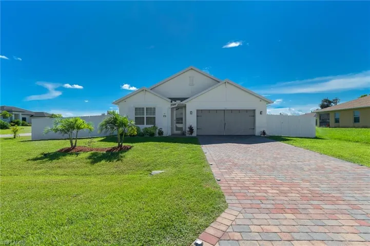 Single story home featuring an attached garage, decorative driveway, and stucco siding