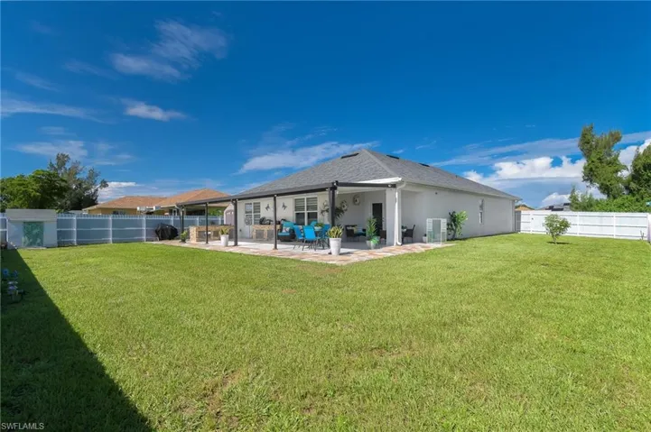 Rear view of property featuring a patio area, a fenced backyard, stucco siding, and roof with shingles