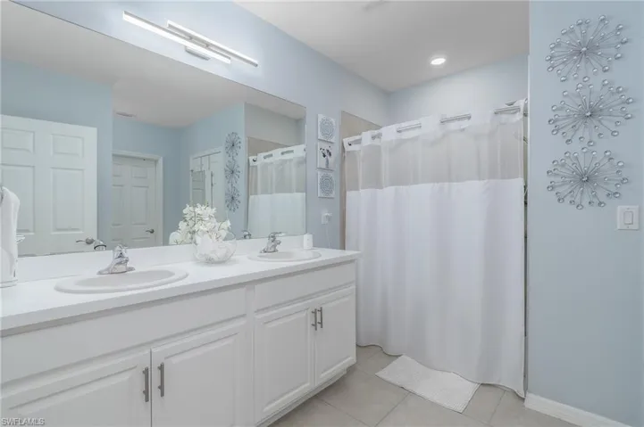 Bathroom with tile patterned flooring, double vanity, and a shower with shower curtain