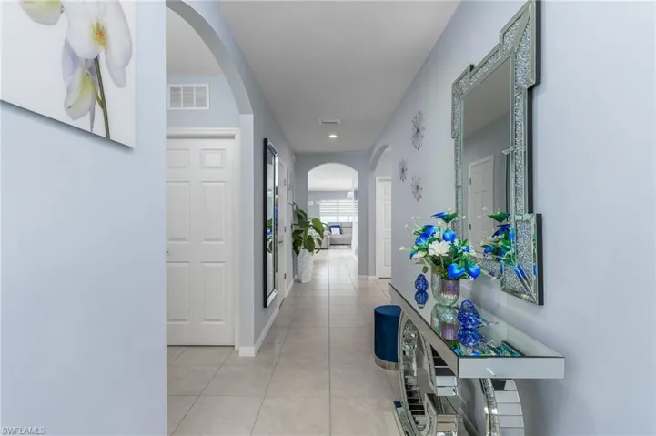 Hallway featuring arched walkways, light tile patterned floors, and recessed lighting