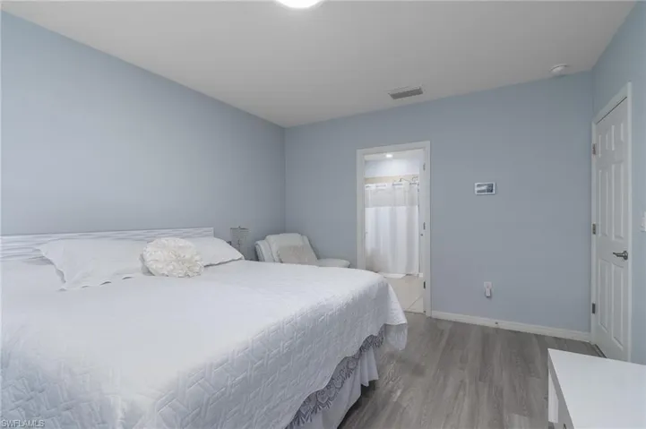 Bedroom with wood finished floors and connected bathroom