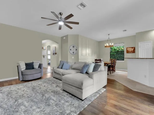 Living room with arched walkways, ceiling fan, wood finished floors, and a chandelier
