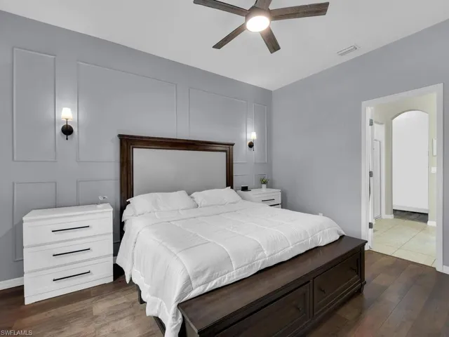 Bedroom featuring dark wood-style floors, arched walkways, and a ceiling fan