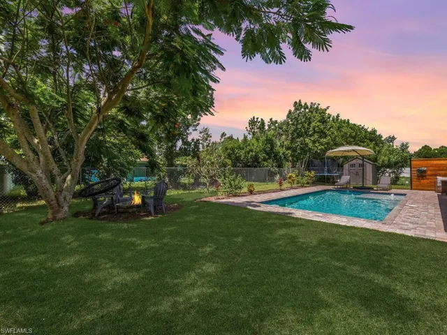 Pool at dusk with a shed, a fenced backyard, an outdoor fire pit, and a patio