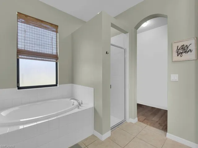 Full bathroom featuring a bath, a stall shower, and tile patterned flooring