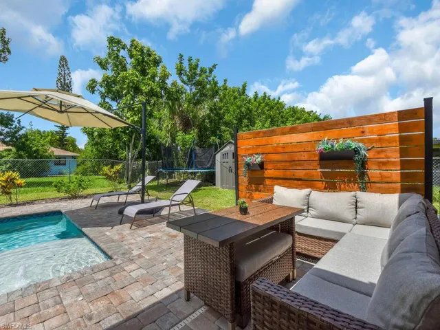 Fenced backyard with a trampoline, a patio area, an outdoor living space, and a shed