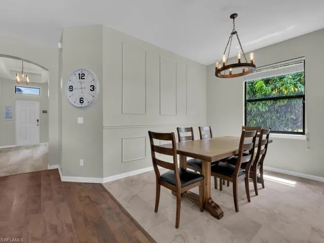 Dining area with a chandelier, arched walkways, and light wood-type flooring